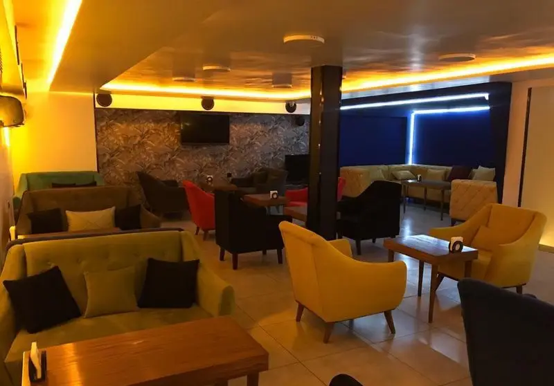 فضای داخلی دنج و مدرن کافه برلین با مبلمان راحتی رنگارنگ، نورپردازی گرم و طراحی دیوار منحصر به فرد برای دورهمی‌ها.