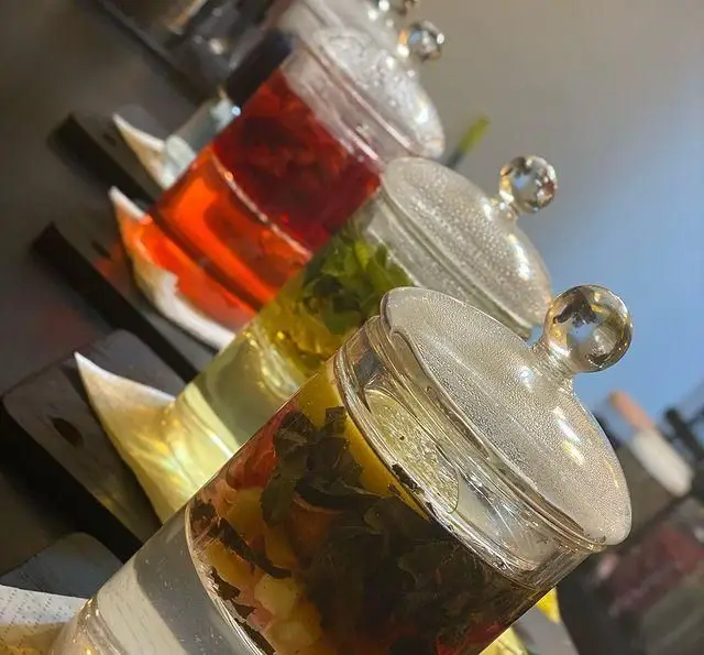 نوشیدنی های متنوع و گوارای کافه برلین: دتاکس واتر و چای سرد میوه ای با تزئینات طبیعی در شیشه های شیک و دربدار، ایده آل برای روزهای گرم.