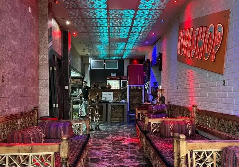 تصویر فضای داخلی دنج و دلنشین کافه قلیان و سفره خانه سنتی کولاک با تخت‌های چوبی، کوسن‌های رنگی، قلیان‌های آماده و نورپردازی خاص.