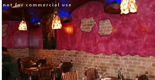 تصویری از فضای داخلی رستوران مورانو با دکوراسیون گرم و دلنشین شامل دیوار آجری، دیوارهای بنفش و میز و صندلی‌های چوبی شیک.