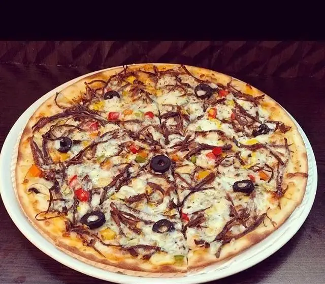 تصویری جذاب از پیتزا مخصوص کافی شاپ میلان. پیتزایی خوشمزه با سس سفید، گوشت ریش ریش، زیتون و فلفل دلمه ای برای تجربه ای لذیذ.