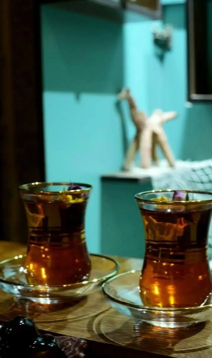 دو فنجان چای دمنوش گل‌محمدی خوش‌عطر در کافه سبز گمرون، فضایی دنج و آرامش‌بخش برای عصرانه یا دورهمی دوستانه.