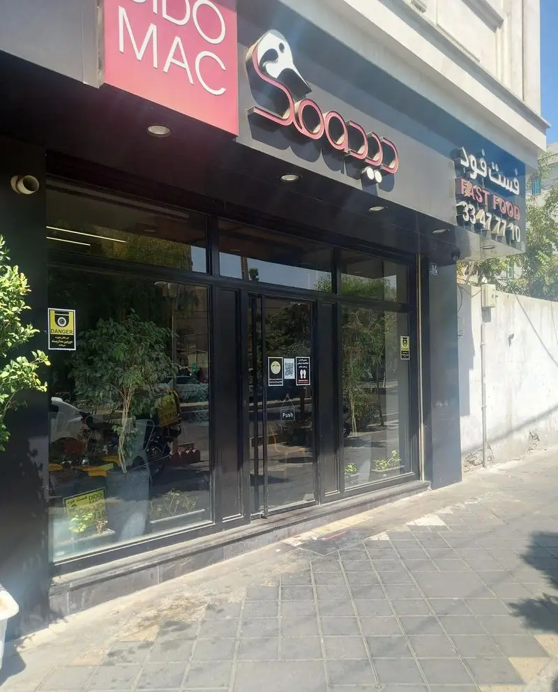 نمای بیرونی کافه و فست فود دیدومک، با تابلوی مشخص شامل لوگو، نام و شماره تماس 33477710، و پنجره‌های بزرگ شیشه‌ای در روز آفتابی.