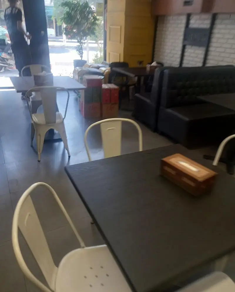 فضای داخلی دنج و مدرن کافه و فست فود دیدومک با میز و صندلی‌های شیک برای تجربه‌ای لذت‌بخش از غذا و نوشیدنی.