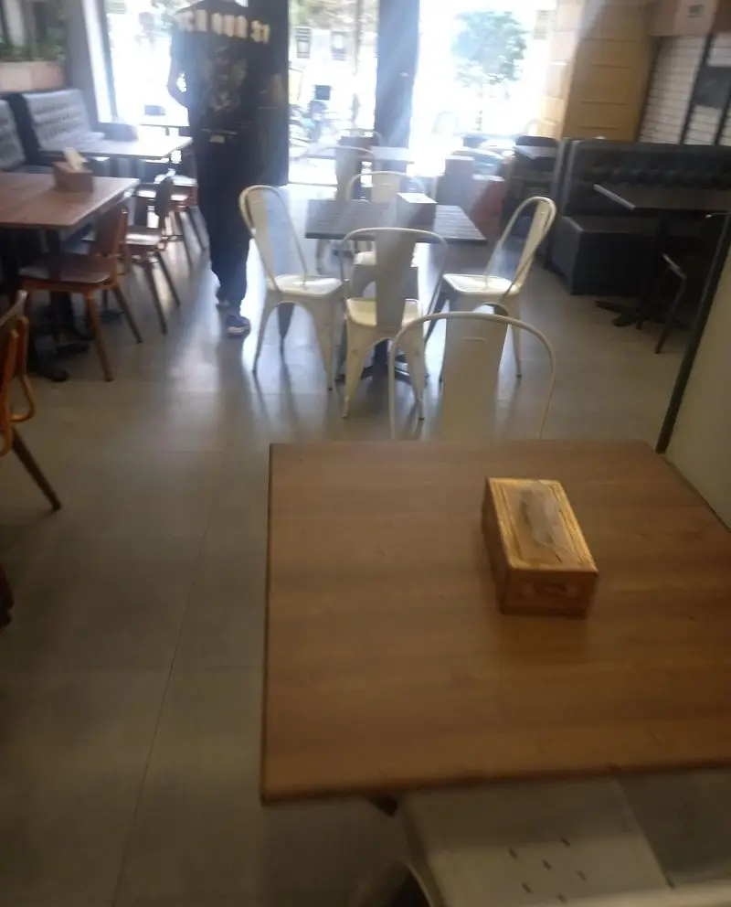 فضای داخلی شیک و مدرن کافه و فست فود دیدومک با میزهای چوبی و صندلی‌های فلزی راحت. محیطی آرام و دلنشین برای صرف انواع غذاها و نوشیدنی‌ها.