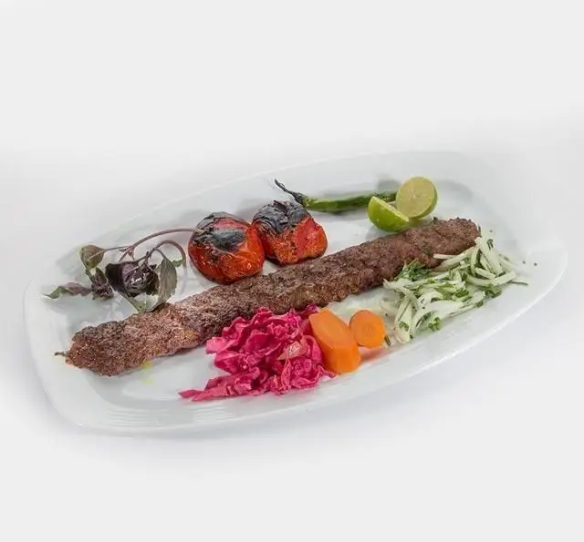 کباب کوبیده ممتاز رستوران وزیری؛ یک وعده غذای سنتی ایرانی با گوجه کبابی، سبزیجات تازه، پیاز، ترشی و لیمو.