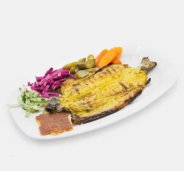 ماهی کبابی زعفرانی رستوران وزیری، غذای دریایی اصیل ایرانی. سرو شده با خیارشور، هویج، کلم قرمز، سبزی تازه و چاشنی.