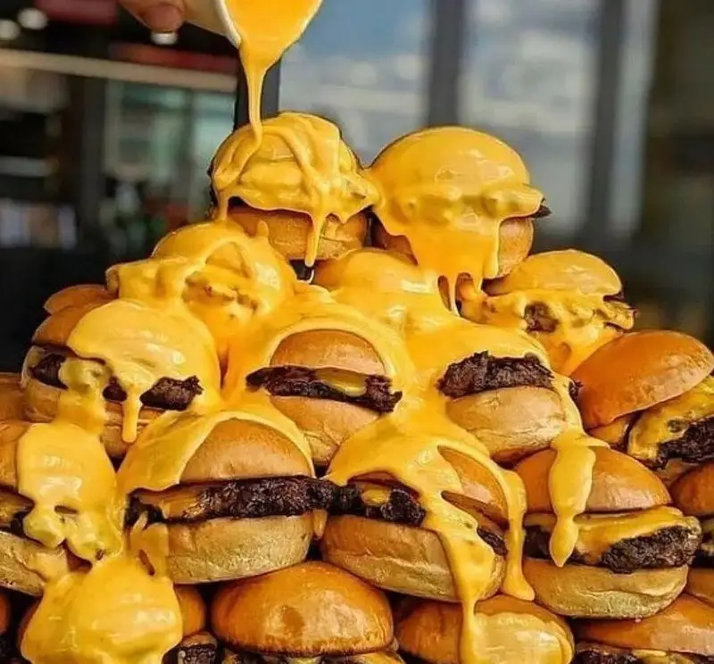 تصویری از برگر دلشاد: کوهی از مینی برگرهای داغ و لذیذ، سرشار از طعم بی‌نظیر پنیر ذوب‌شده طلایی.
