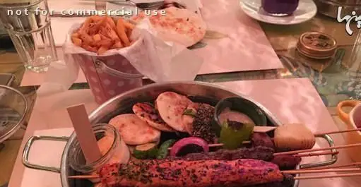 میز پر از غذاهای لذیذ رستوران کوبابا شامل انواع کباب‌های کوبیده و جوجه به همراه نان‌های تازه، سیب زمینی سرخ کرده و سس‌های متنوع.