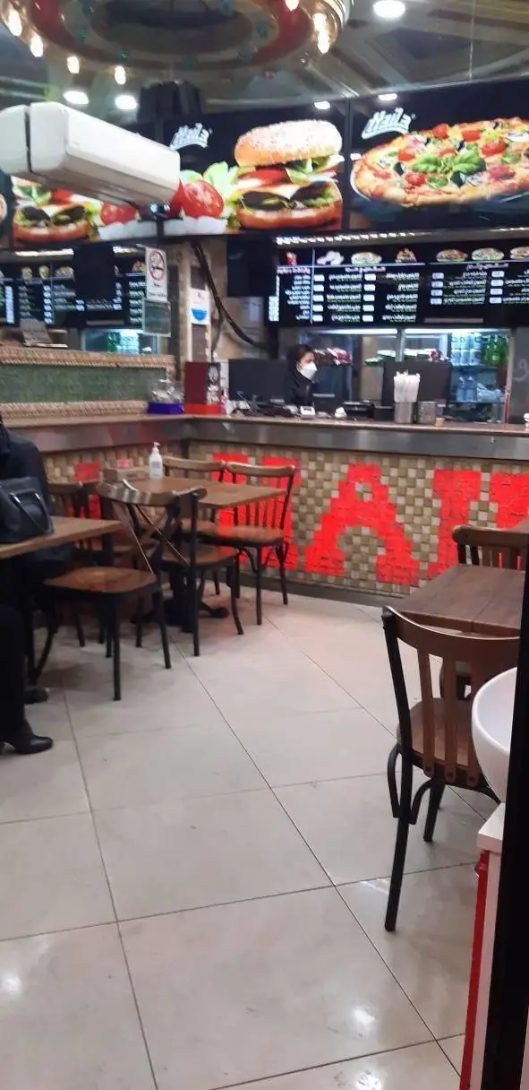 فضای داخلی فست فود هایلا با نمایش منوی کامل شامل انواع برگر و پیتزا، میز و صندلی‌های تمیز و پیشخوان سفارشات مشتریان.