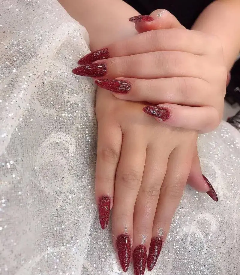مدل کاشت ناخن تیز و بلند با لاک ژل قرمز اکلیلی شایندار و براق روی دست زنانه با پسزمینه پارچه تور سفید درخشان و زیبا