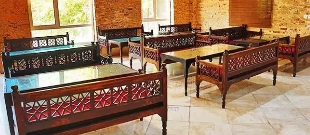 فضای داخلی رستوران ایرانی گل یخ با نیمکت‌ها و میزهای چوبی سنتی و کنده‌کاری‌شده، دکوراسیون دلنشین و اصیل.