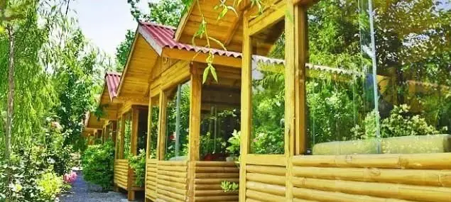 آلاچیق‌های چوبی و شیشه‌ای رستوران ایرانی گل یخ، در فضایی سرسبز و آرامش‌بخش، مناسب برای صرف غذا و لذت بردن از طبیعت.