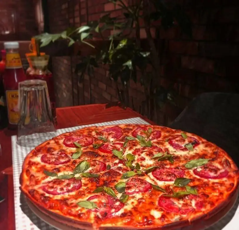 پیتزای لذیذ ایتالیایی با پنیر فراوان، گوجه تازه و ریحان معطر در رستوران مازتی؛ تجربه‌ای بی‌نظیر برای دوستداران پیتزا.