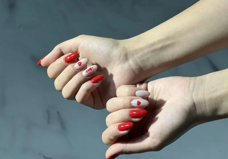 طراحی ناخن دخترانه با لاک قرمز جذاب و طرح قلب فانتزی مناسب برای ولنتاین و کاشت ناخن شیک روی ناخنهای کشیده و زیبا