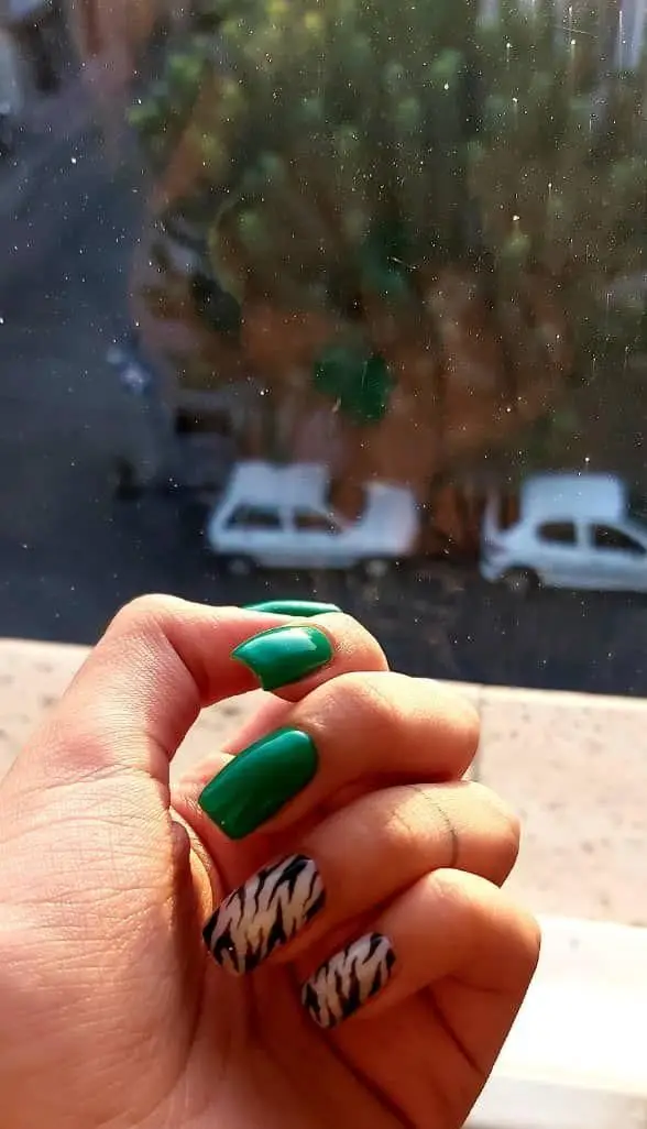 طراحی ناخن شیک با لاک سبز تیره و طرح گورخری سیاه و سفید روی ناخنهای دست در سالن زیبایی ماه بیوتی برای خدمات کاشت ناخن