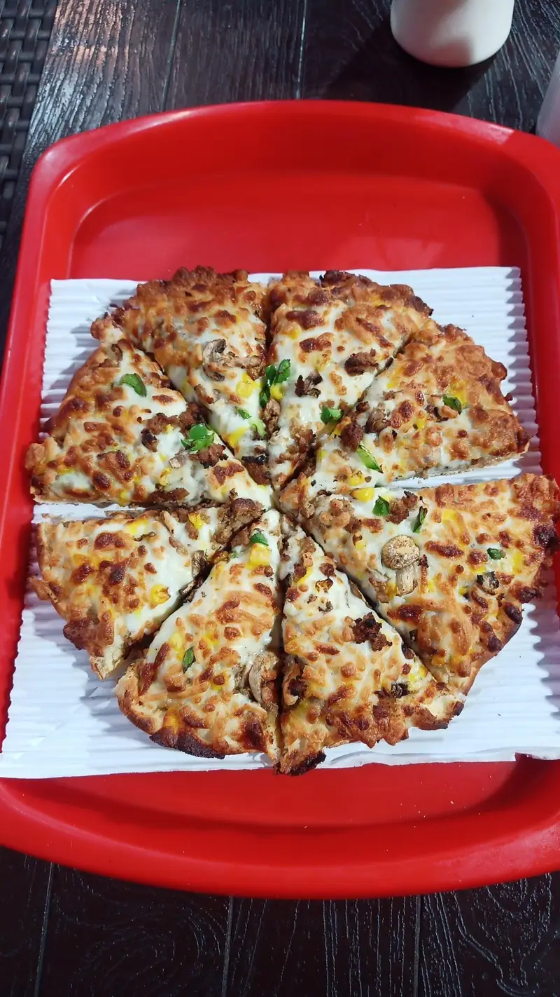 پیتزای مخصوص بمب جنت آباد با نان ترد و پنیر طلایی، مزین به گوشت، قارچ و ذرت. بهترین انتخاب فست فود در منطقه جنت آباد تهران.