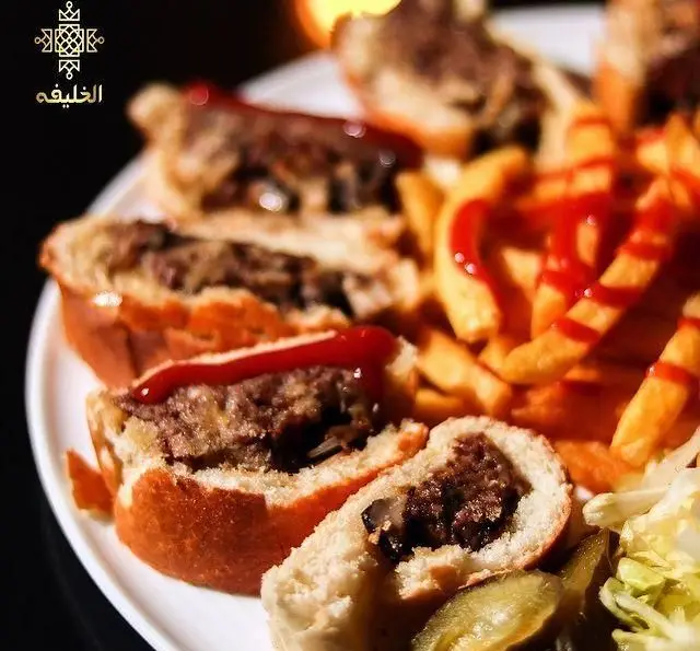بشقاب ساندویچ‌های لقمه‌ای خوشمزه با گوشت، روکش کچاپ، سیب‌زمینی سرخ کرده فراوان و ترشی در رستوران و کافه الخلیفه.
