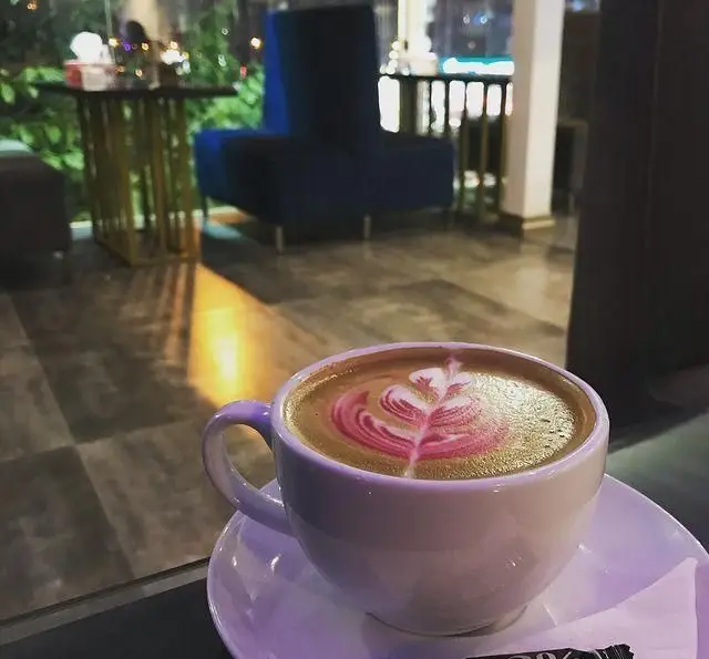 قهوه لاته با لاته آرت صورتی جذاب در محیط شیک و دلپذیر رستوران و کافه الخلیفه، مکانی ایده‌آل برای اوقاتی خوش و نوشیدنی.