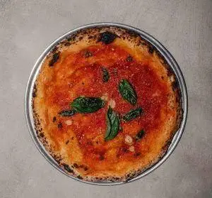 پیتزا خوشمزه ناپولیتن رستوران فرسکو با سس گوجه تازه و برگ‌های ریحان، مناسب برای ناهار یا شام. تجربه غذای ایتالیایی عالی.