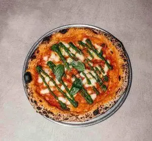 پیتزا ناپلی خوشمزه رستوران فرسکو با سس قرمز، پنیر موزارلا، سس سبز پستو و برگ‌های تازه ریحان، بهترین انتخاب برای ناهار و شام.