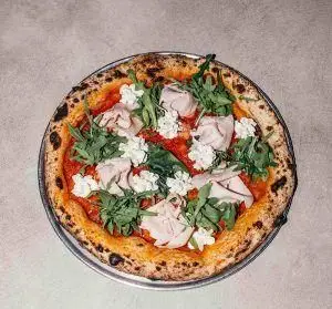 پیتزا ناپلی اصیل و خوش‌طعم رستوران فرسکو با خمیر برشته، سس گوجه، تکه‌های ژامبون، برگ راکت تازه و پنیر خامه‌ای.