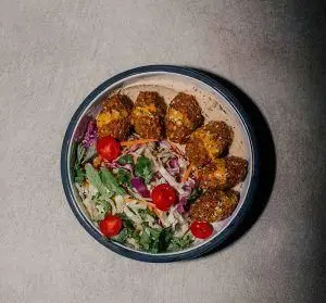 کاسه سلامت رستوران فرسکو با کوفته‌های ترد، سالاد تازه کلم و سبزیجات، گوجه گیلاسی و دیپ خامه‌ای. غذای سالم و خوشمزه برای ناهار یا شام.