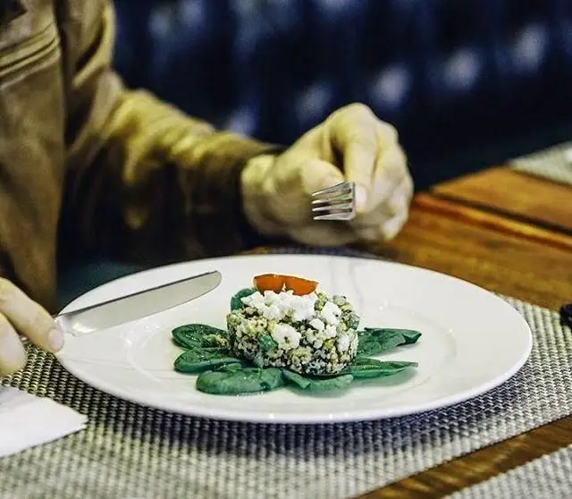 مشتری در کافی شاپ بلوار از غذایی زیبا و سالم شامل کینوا، اسفناج و پنیر لذت می‌برد. تجربه‌ای دلنشین با سرویس باکیفیت.