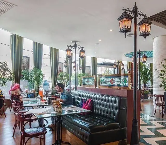 فضای داخلی جذاب کافی شاپ بلوار با دکوراسیون خاص شامل نیمکت چرمی، نورپردازی منحصر به فرد و محیطی دلپذیر برای مشتریان.