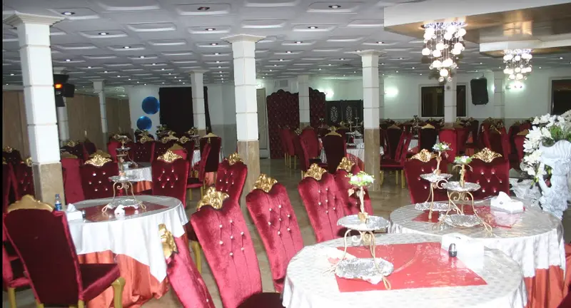 تصویری از تالار پذیرایی مجلل چهلستون با چیدمان میز و صندلی‌های مخمل قرمز سلطنتی برای مراسم عروسی و مهمانی‌ها.