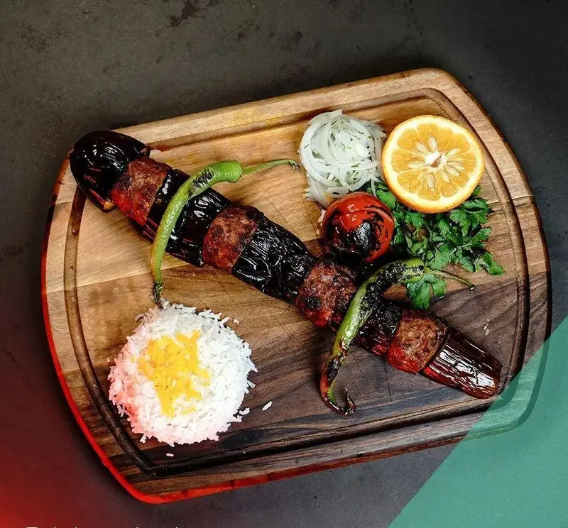 کباب بادمجان و گوشت لذیذ ترکی با برنج، فلفل کبابی، گوجه، پیاز و پرتقال، انتخابی عالی در رستوران ترکی تورکواز.