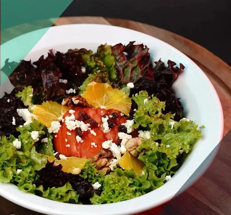 سالاد تازه و اشتهاآور رستوران ترکی تورکواز، شامل کاهوهای متنوع، گوجه، پنیر فتا، پرتقال و گردو. انتخابی سالم و خوشمزه.