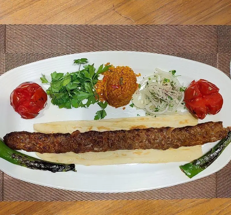 کباب آدانا لذیذ رستوران ترکی تورکواز: کباب، بلغور پلو، گوجه، فلفل کبابی، پیاز و سبزیجات تازه. غذایی اصیل و خوشمزه.