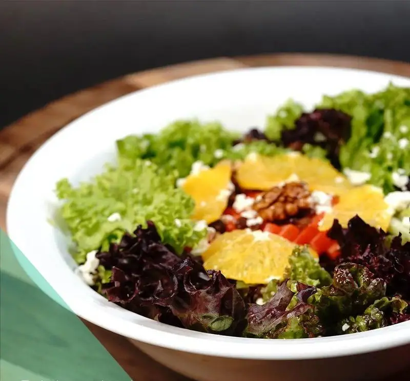 سالاد رنگارنگ و سالم رستوران ترکی تورکواز با کاهو، پرتقال، گردو و پنیر فتا. انتخابی عالی برای رژیم غذایی.