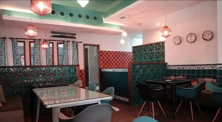 تصویری از دکوراسیون داخلی شیک و خاص کافی شاپ ایل، با طراحی منحصربه‌فرد، مبلمان راحت، کاشی‌های رنگی و محیطی آرامش‌بخش برای مشتریان.