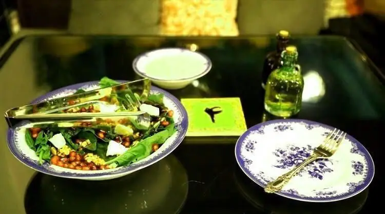 سالاد تازه با انار و اسفناج در کافی شاپ ایل، آماده سرو با سس مخصوص و چنگال. تجربه یک وعده غذایی سالم و دلپذیر در محیطی دنج.