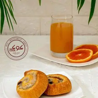 کافه قنادی کوک: شیرینی‌های تازه و خوشمزه، همراه با آب پرتقال طبیعی و برش‌های پرتقال برای یک صبحانه یا میان‌وعده دلپذیر. محصولات باکیفیت کوک.