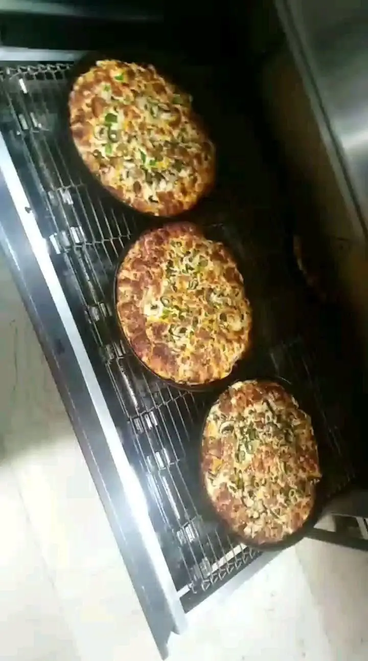 پیتزاهای داغ و خوشمزه فست فود بوبوک مشیریه، با انواع قارچ، فلفل دلمه‌ای و مواد اولیه تازه، در حال پخت در فر و آماده ارسال.