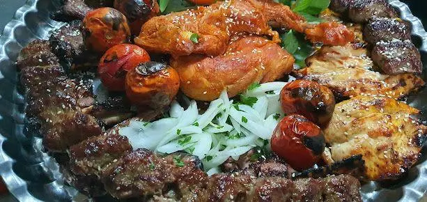 سینی بزرگ کباب میکس متنوع و خوشمزه از سفره خانه سنتی عیاران، شامل جوجه کباب، کباب گوشت، گوجه و پیاز گریل شده، غذای اصیل ایرانی.