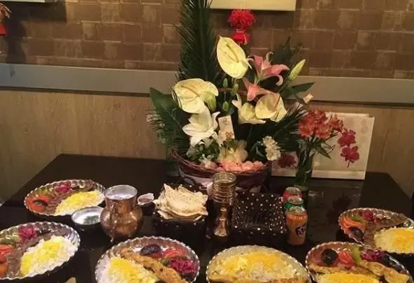میز غذای آماده در کافه رستوران آدا با کباب‌های اصیل، برنج زعفرانی و تزئینات گل. محیطی دلنشین برای تجربه‌ غذای باکیفیت ایرانی.