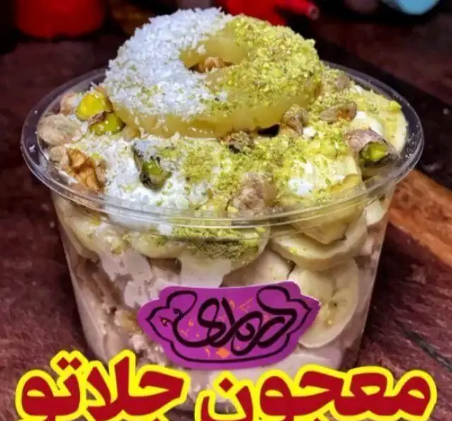 تصویر معجون جلاتو درباری، دسر لیوانی جذاب با لایه‌های موز، آناناس، خامه، پسته، گردو و نارگیل. انتخابی ویژه و خوش طعم.