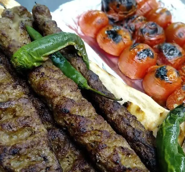سفره‌ای شاهانه از کباب کوبیده اصیل کبابی منیریه، همراه با فلفل سبز کبابی و گوجه‌های آبدار کبابی، آماده سرو برای شما.