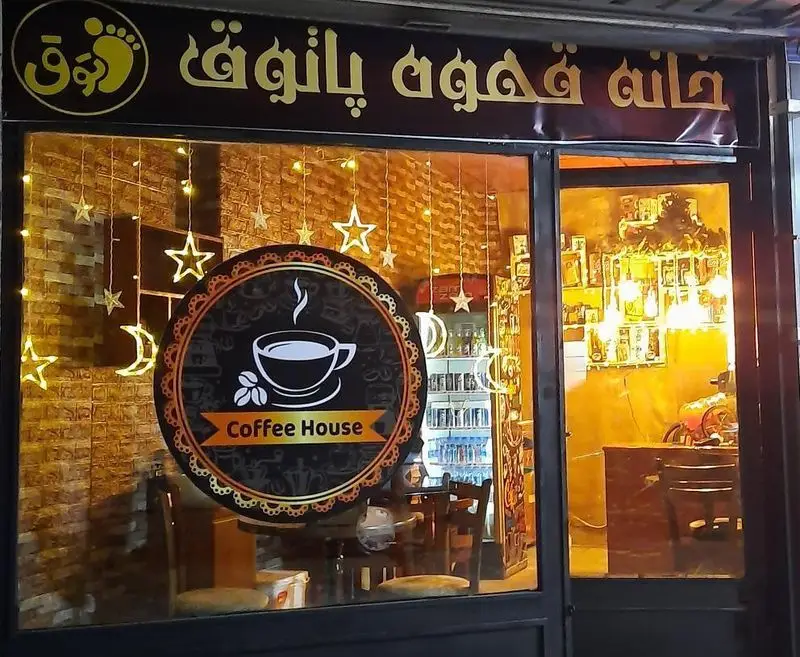 نمای شبانه کافه قهوه پاتوق با تابلوی خانه قهوه و لوگوی اختصاصی، دکوراسیون داخلی گرم و نورپردازی جذاب، مکانی دنج و ایده‌آل برای دوستداران قهوه.