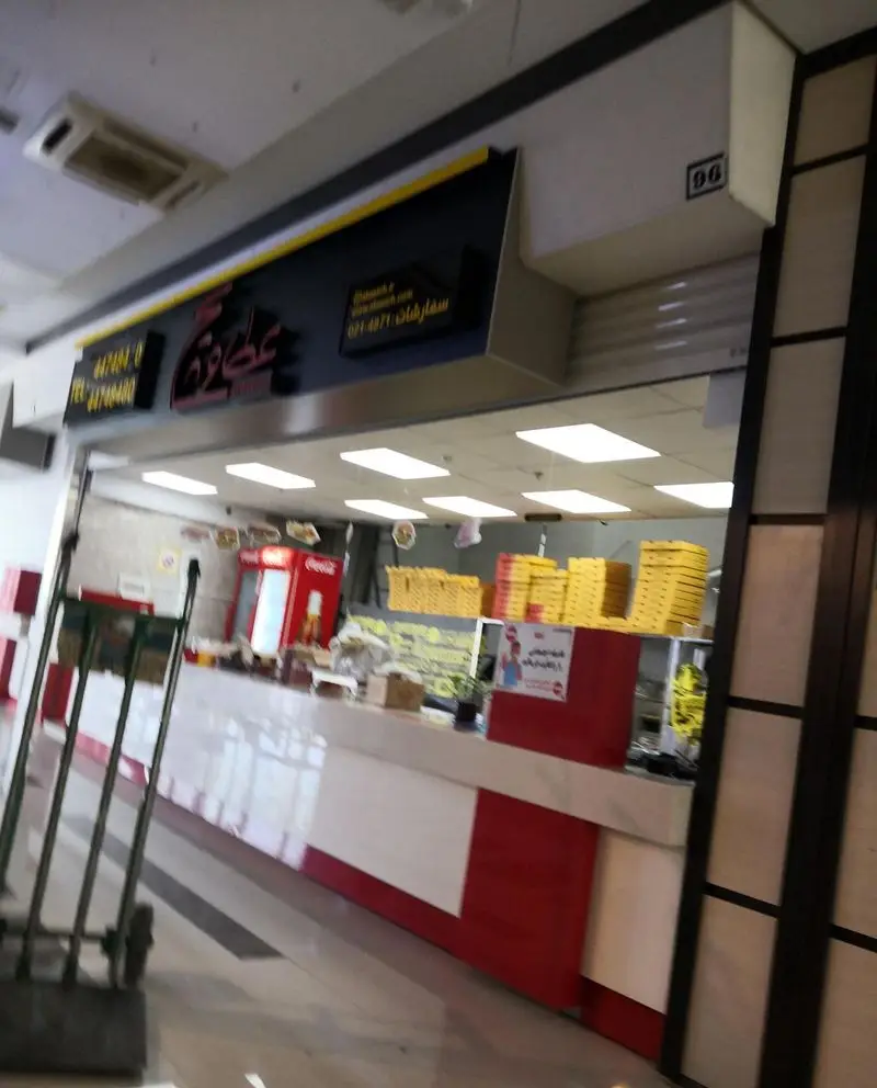 تصویری از فودکورت عطاویچ خلیج فارس با تابلو اطلاعات تماس و شماره سفارش، پیشخوان خدمات و جعبه‌های آماده فست فود.