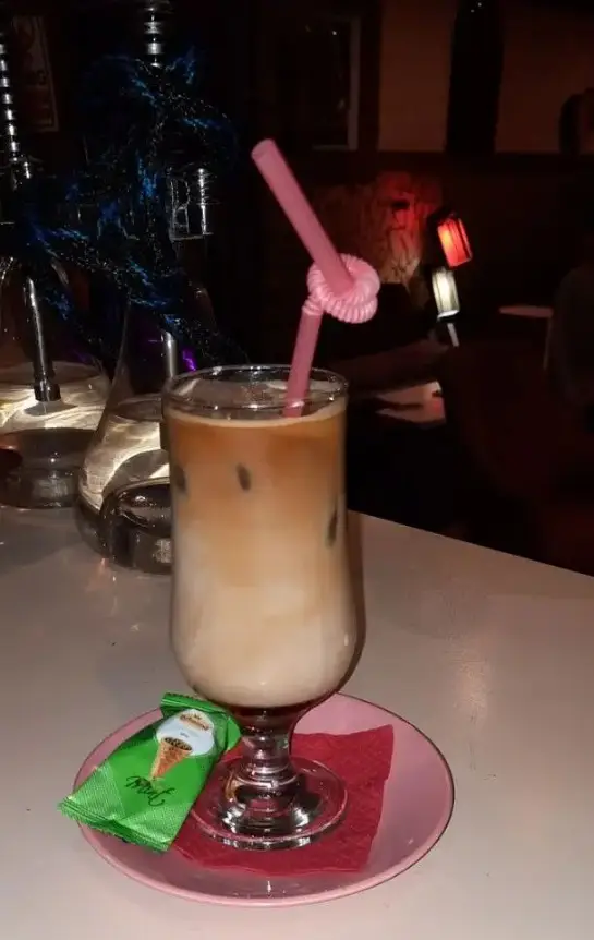 آیس کافی خنک با نی صورتی در فضای دلنشین کافه سنتی ایران زمین، مکانی دنج برای نوشیدنی و قلیان. تجربه ای خاص.