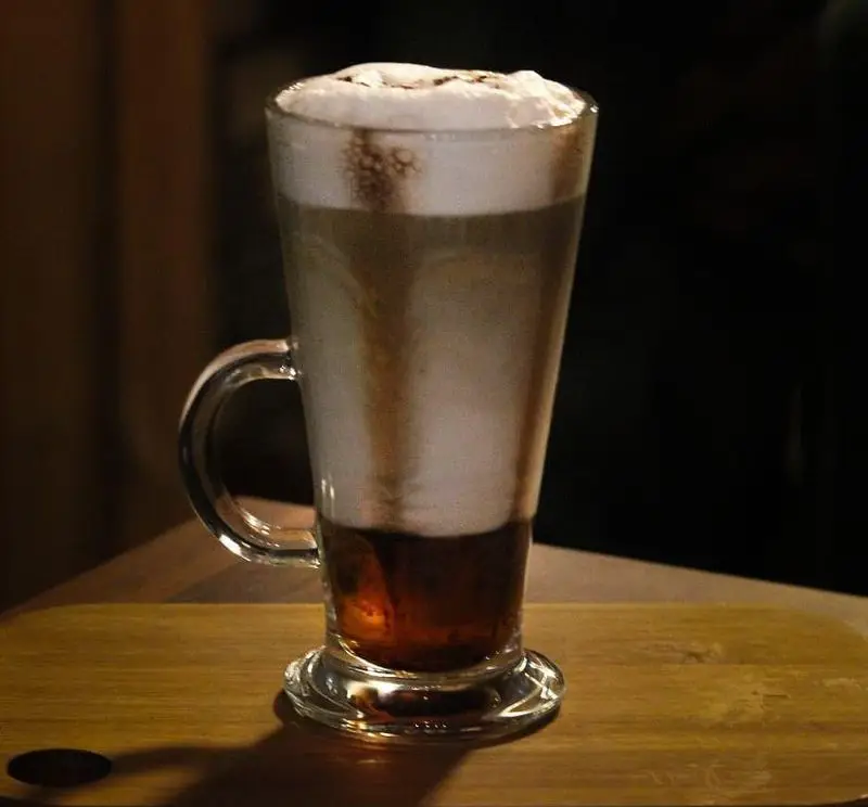 قهوه لایه ای جذاب و خوش طعم کافه رستوران دیاکو، شامل اسپرسو، شیر و فوم غلیظ روی میز چوبی زیبا در محیطی دلنشین.