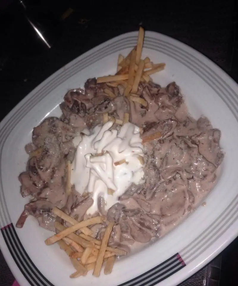 خوراک بیف استروگانف خامه‌ای با تکه‌های گوشت، قارچ، خامه ترش و سیب‌زمینی ترد از رستوران شبهای شیراز.