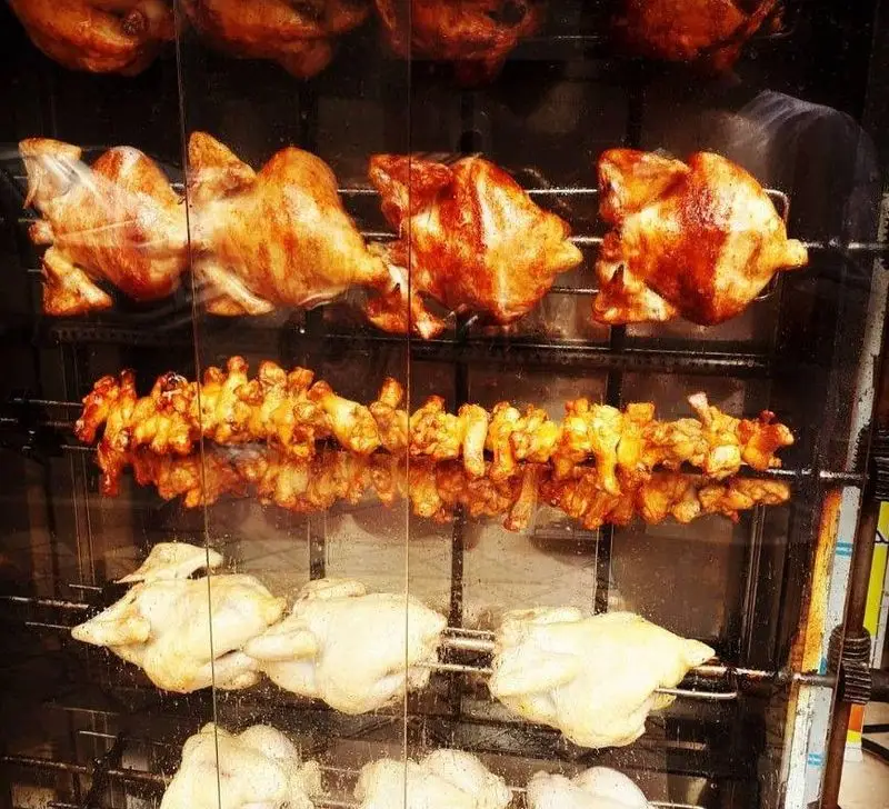 مرغ بریان و جوجه گردان داغ و تازه فست فود بهنام. نمایش مرغ‌های کامل در مراحل مختلف پخت، از خام تا کاملاً بریان، به همراه سیخ بال و کتف.