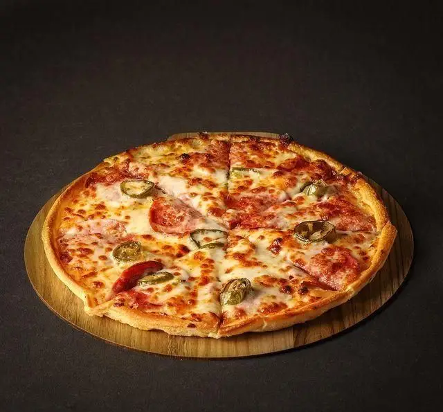 پیتزای خوشمزه پپرونی و فلفل هالاپینو با پنیر فراوان بر روی تخته چوبی در کافه رستوران لی وان، آماده سرو.