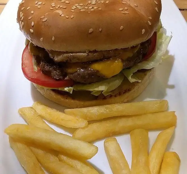 دبل چیزبرگر آبدار و خوشمزه کافه رستوران لی وان با نان کنجدی، پنیر، کاهو، گوجه و سیب‌زمینی سرخ کرده طلایی.